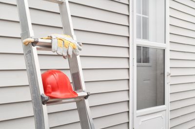 Professional installing siding on a ladder